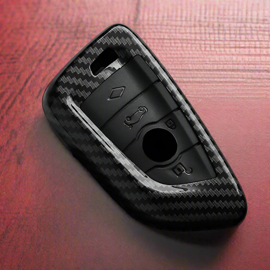 Black car key fob cover with carbon fiber texture on a dark surface