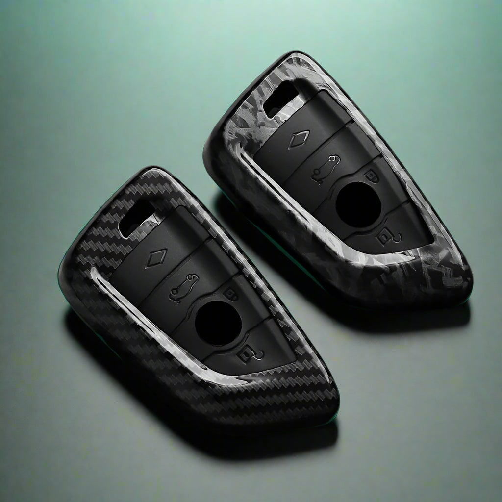 Two black car key fobs with carbon fiber texture on a dark surface, featuring the brand 'AEYG'.