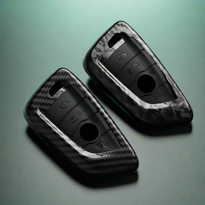 Two black car key fobs with carbon fiber texture on a dark surface, featuring the brand 'AEYG'.